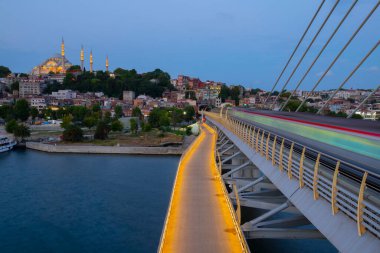İstanbul 'da metro, Haliç yer istasyonu, Fatih ilçesi ve arkada Süleyman camisi, köprüde yürüyen insanlar, gün batımı