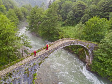 Eski taş köprüler ve çay taşıyan kadınlar.