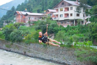 Firtina Nehri üzerinde çelik halatla kayma sporu yapan turist Camlihemsin, Rize, Türkiye 'de eğleniyor.