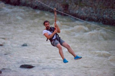 Firtina Nehri üzerinde çelik halatla kayma sporu yapan turist Camlihemsin, Rize, Türkiye 'de eğleniyor.