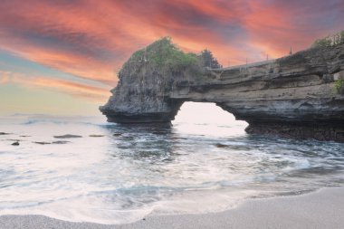 Endonezya 'daki Pura Batu Bolong' da doğal kaya mağarası oluşumu ve gün batımında el sallama