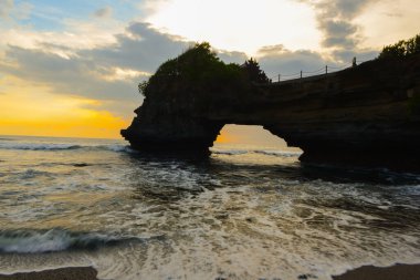 Endonezya 'daki Pura Batu Bolong' da doğal kaya mağarası oluşumu ve gün batımında el sallama