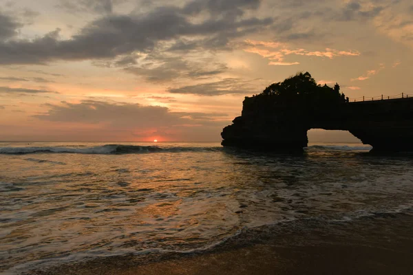 印度尼西亚Pura Batu Bolong自然岩洞的形成和日落时的波浪 — 图库照片