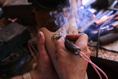 Bir adam bir ağaç resmi yakıyor. Tahtaya biyografik oyma. Pirografi.