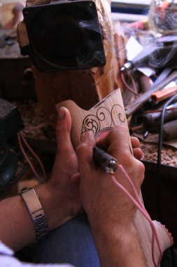 Bir adam bir ağaç resmi yakıyor. Tahtaya biyografik oyma. Pirografi.