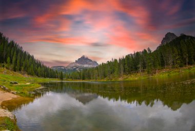 İtalya 'nın Dolomitler şehrinde sonbaharda gün doğumunda doğan dağların yansımasıyla. Antorno gölü manzarası, suyun üzerindeki mavi sis, portakal yapraklı ağaçlar ve sonbaharda yüksek kayalar. Renkli orman