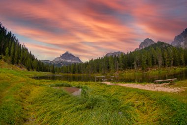 İtalya 'nın Dolomitler şehrinde sonbaharda gün doğumunda doğan dağların yansımasıyla. Antorno gölü manzarası, suyun üzerindeki mavi sis, portakal yapraklı ağaçlar ve sonbaharda yüksek kayalar. Renkli orman