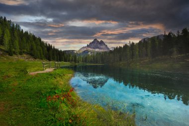 İtalya 'nın Dolomitler şehrinde sonbaharda gün doğumunda doğan dağların yansımasıyla. Antorno gölü manzarası, suyun üzerindeki mavi sis, portakal yapraklı ağaçlar ve sonbaharda yüksek kayalar. Renkli orman