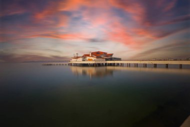 Sahilde bir rıhtım ve batık bir gemi, uzun pozlama tekniğiyle fotoğraflanmış.