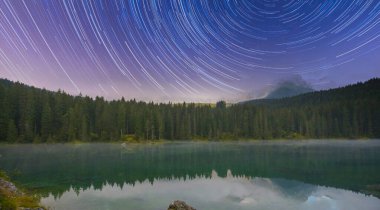 Lago di Carezza, doğanın büyüleyici panoramasına dokunmuş görkemli Dolomitler tarafından çerçevelenmiş ladin ağaçlarıyla bezenmiş zümrüt suları olan bir alp mucizesi.
