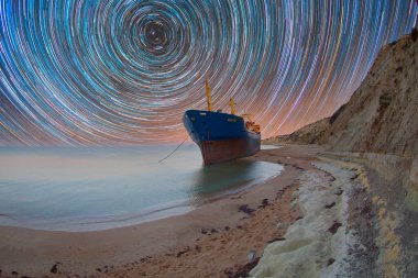 Kıyıya vurmuş bir gemi, gece gündüz fotoğraflanmış.