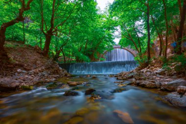 The old stone, arched bridge, between two waterfalls in Palaiokaria, Trikala prefecture, Thessaly, Greece. clipart