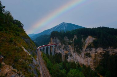 Dağda viyadük üzerinde İsviçre kırmızı treni, manzaralı yolculuk