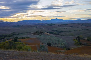 Arka planda Val d 'Orcia tepeleri olan Ascanio yakınlarındaki bir çiftlik evinin panoramik görüntüsü