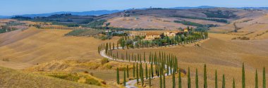 Arka planda Val d 'Orcia tepeleri olan Ascanio yakınlarındaki bir çiftlik evinin panoramik görüntüsü