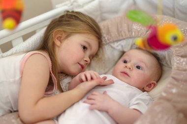 Beşikteki küçük kardeşiyle oynayan küçük şirin bir kızın yakın çekimi.