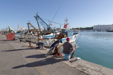 Trani, Italy - October 29, 2023: Men fishing at the Trani harbour clipart