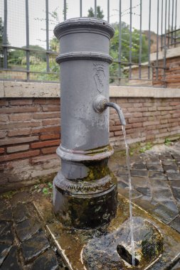 Typical ancient Roman drinking water fountain on street clipart