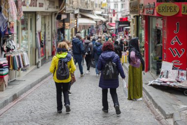 İstanbul, Türkiye - 11 Kasım 2024: İstanbul Eminnonu semtindeki Baharat Çarşısı etrafındaki dar sokakları dolduran tezgahlar arasından alışveriş yapanlar geçiyor