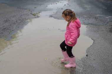 Çizmeli çocuk derin bir su birikintisine atlıyor.