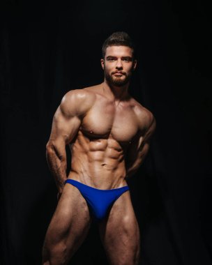 Siyah arka planda mayo giyen seksi kaslı adam. Stüdyoda sakalsız erkek model. Spor salonundaki adam portresi..