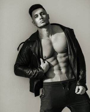 Deri ceketli yakışıklı bir adamın siyah beyaz portresi. Vahşi görünüşlü seksi erkek model. Kaslı adamın bisiklet stili fotoğrafı..
