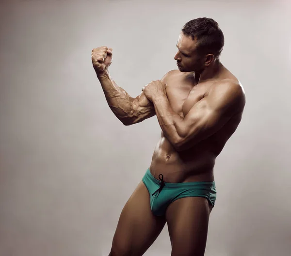 Vyčiněný Sportovec Tyrkysových Plavkách Mužský Model Zkoumá Své Velké Bicepsy — Stock fotografie