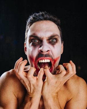 Stüdyoda şakacı suratlı bir adamın portresi. Cadılar Bayramı kahramanı yüz sanatı ile kapat.