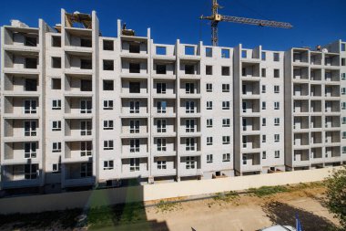 Rising Horizons: A Steel Skeleton of Future Living - Bir apartman dairesi mavi gökyüzü zeminine ve dağınık bulutlara karşı şekil alır,.
