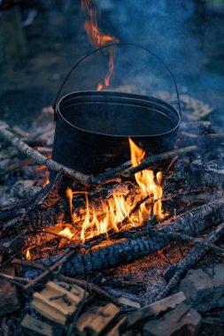 Közler Bir Kazanın Altında Dans Et: Kükreyen bir kamp ateşinin üzerinde kaynayan zamansız bir demlik, çatırdayan odunlar ve yıldızlı bir gecenin sıcaklığıyla çevrili..