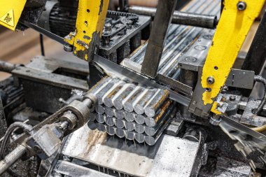 Hareketlerde hassasiyet: Metal kesme makinesi çelik çubukları keser, endüstriyel sanatlarda ham güç ve işçilik sergiler.