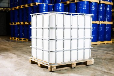 Industrial Harmony: A Sturdy Liquid Storage Container Nestled on a Pallet, Surrounded by a Sea of Vibrant Blue Barrels! clipart