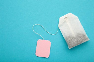 Mavi arka planda pembe boş etiketli çay poşeti. Uzayı metin için kopyala. Üst görünüm