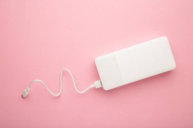 Pembe arka planda USB kablosu olan taşınabilir bir güç bankası. Üst görünüm