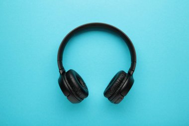 Mavi arka planda siyah, modern kablosuz kulaklıklar. Üst görünüm.