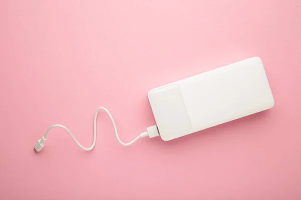 stock image Portable powerbank with usb cable on pink background. Top view