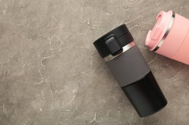 Gri arka planda çay ya da kahve için iki termo bardak ya da termos bardağı. Adam ve kadın için siyah ve pembe. Çiftler için sıcak içecek. Üst görünüm