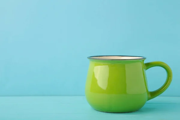 Green mug on blue background with copy space. Top view.