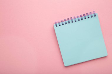Blue notebook on pink background with copy space. Top view.