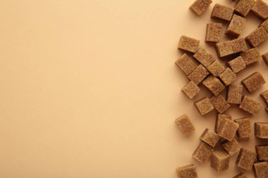 Brown sugar cubes on beige background with space for text. Top view