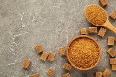 Brown sugar and sugar cubes on grey background. Top view. Space for text