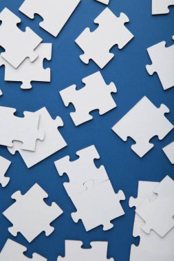 Uncompleted elements of a white puzzle on blue background. Vertical photo