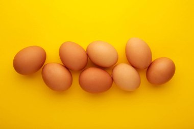Chicken eggs on yellow background. Farm products, natural eggs. Top view