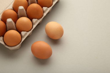 Chicken eggs in an open egg carton on grey. Natural healthy food and organic farming concept.