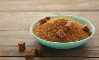 Brown sugar and sugar cubes on grey wooden background. Top view. Space for text