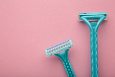 Blue razors for hair removal on pink background. Top view