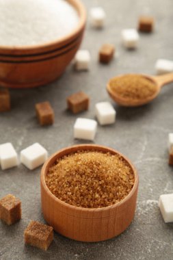 White and brown sugar in bowl on grey background. Vertical photo. Top view