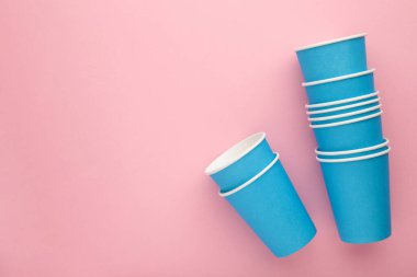 Paper blue disposable cup on pink background. Top view