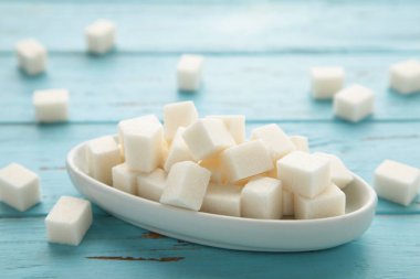 Sugar cubes in a bowl on blue background. Top view
