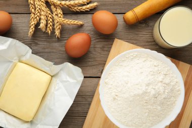 Ingredients for baking or cooking, egg flour, rolling pin butter, milk on a grey wooden background Cookie pie or cake recipe. Top view.